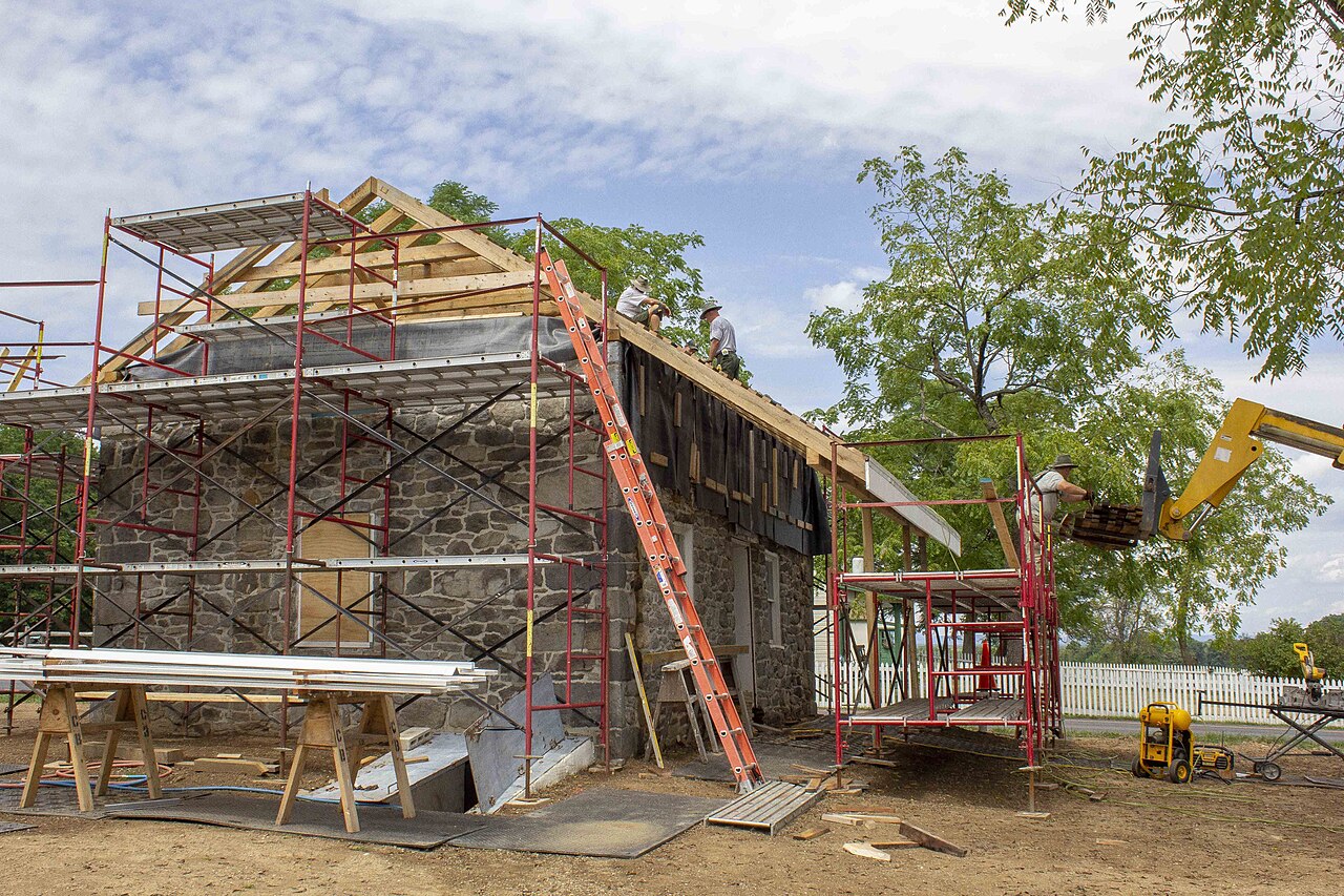 Roofers rebuilding a stone house roof with new shingles