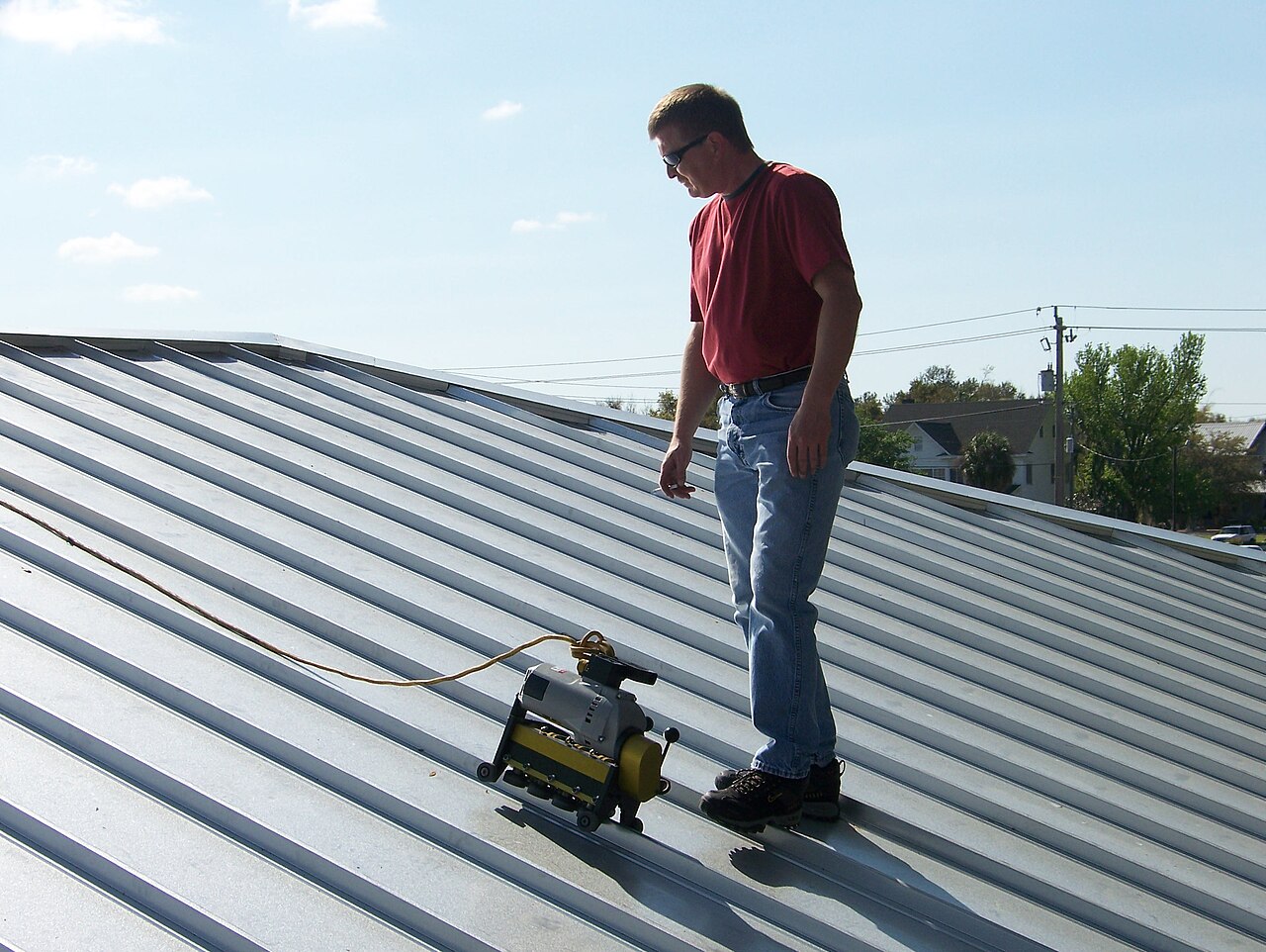 Worker seaming a standing-seam metal roof